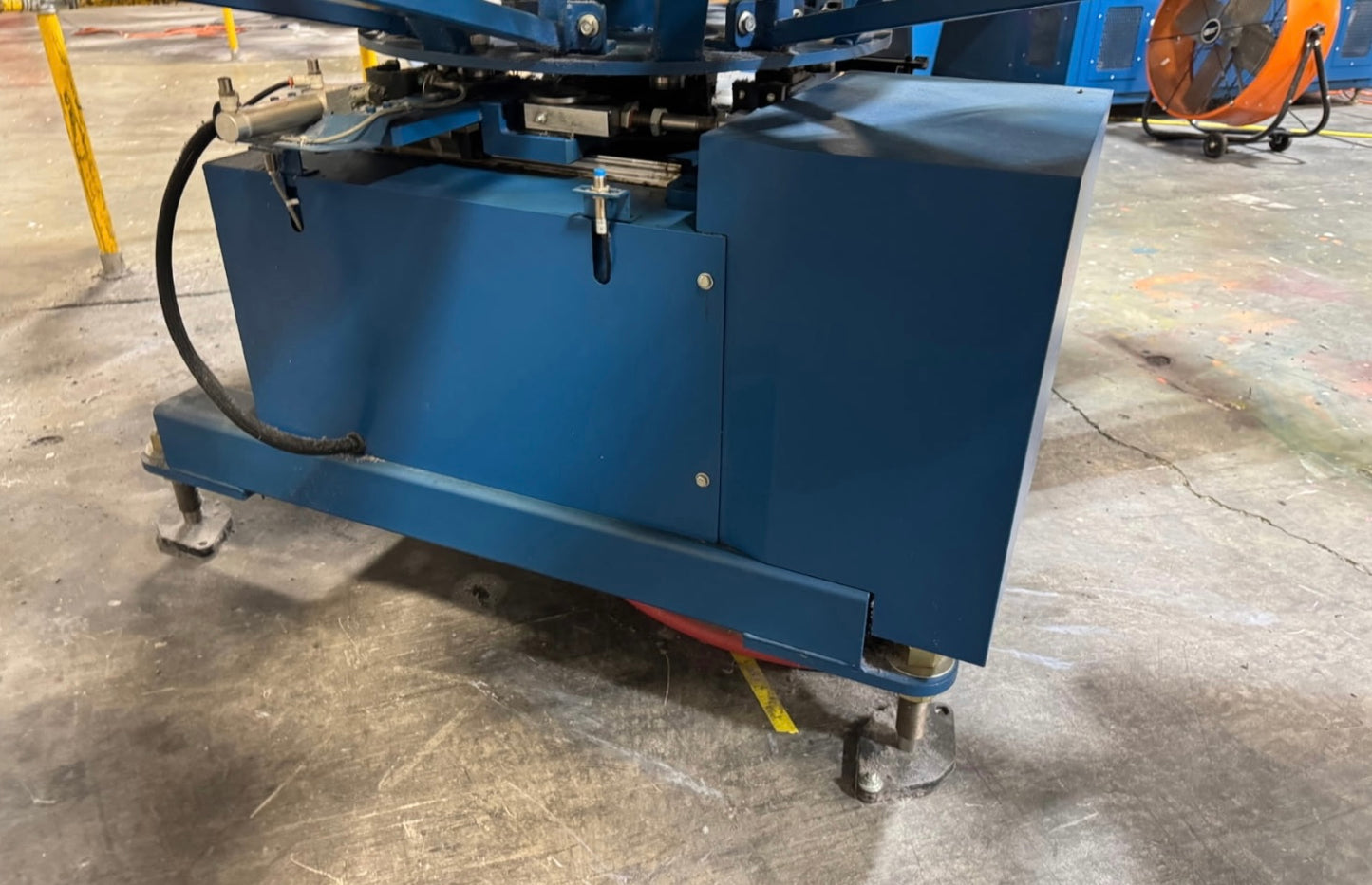 Blue industrial machine on a concrete floor with visible wear and rust.